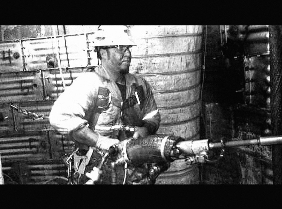 Black-and-white photograph of a worker operating a drill underground.